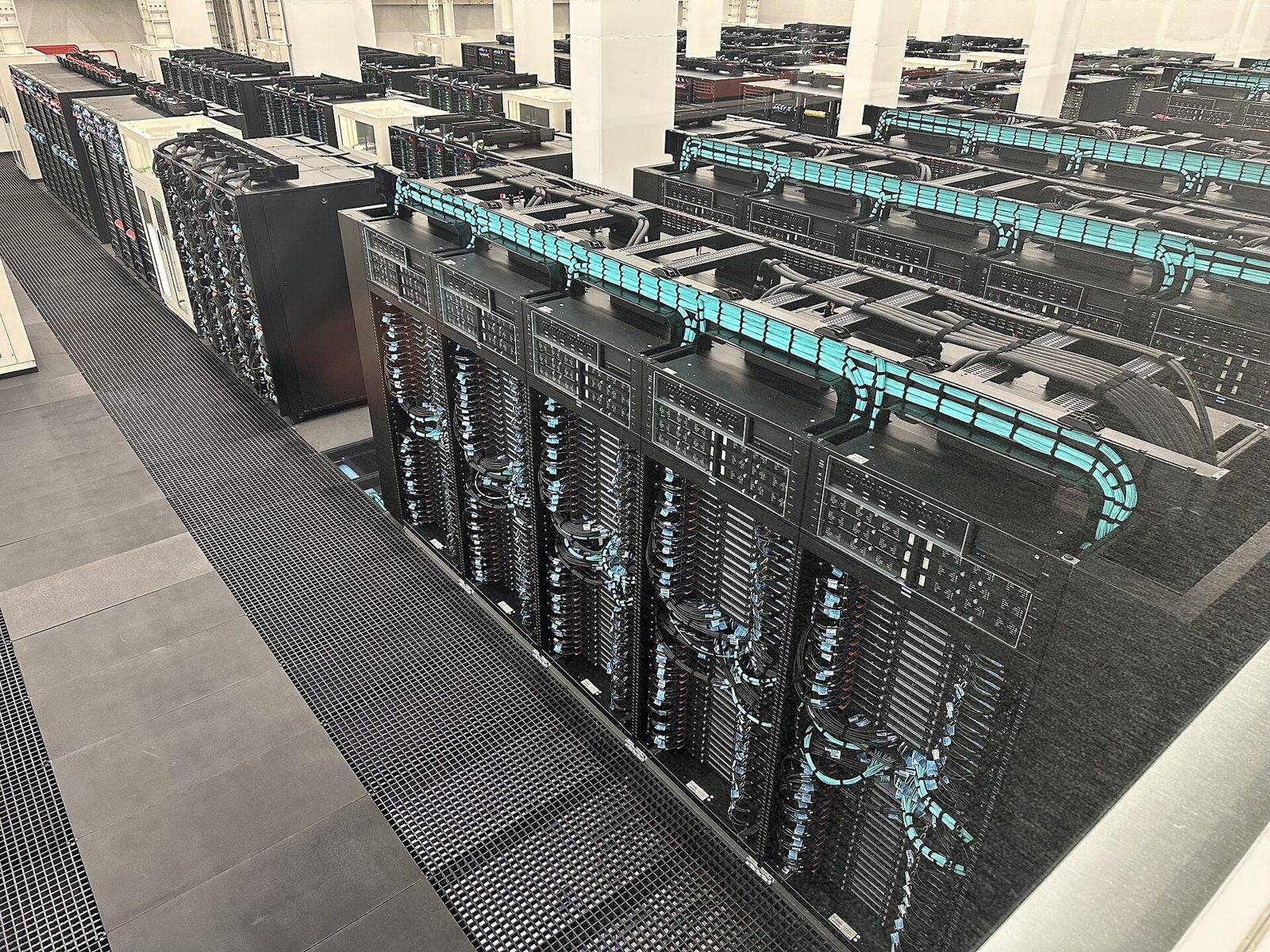 Filas de armarios del superordenador MareNostrum 5 con cableado turquesa en el Barcelona Supercomputing Center